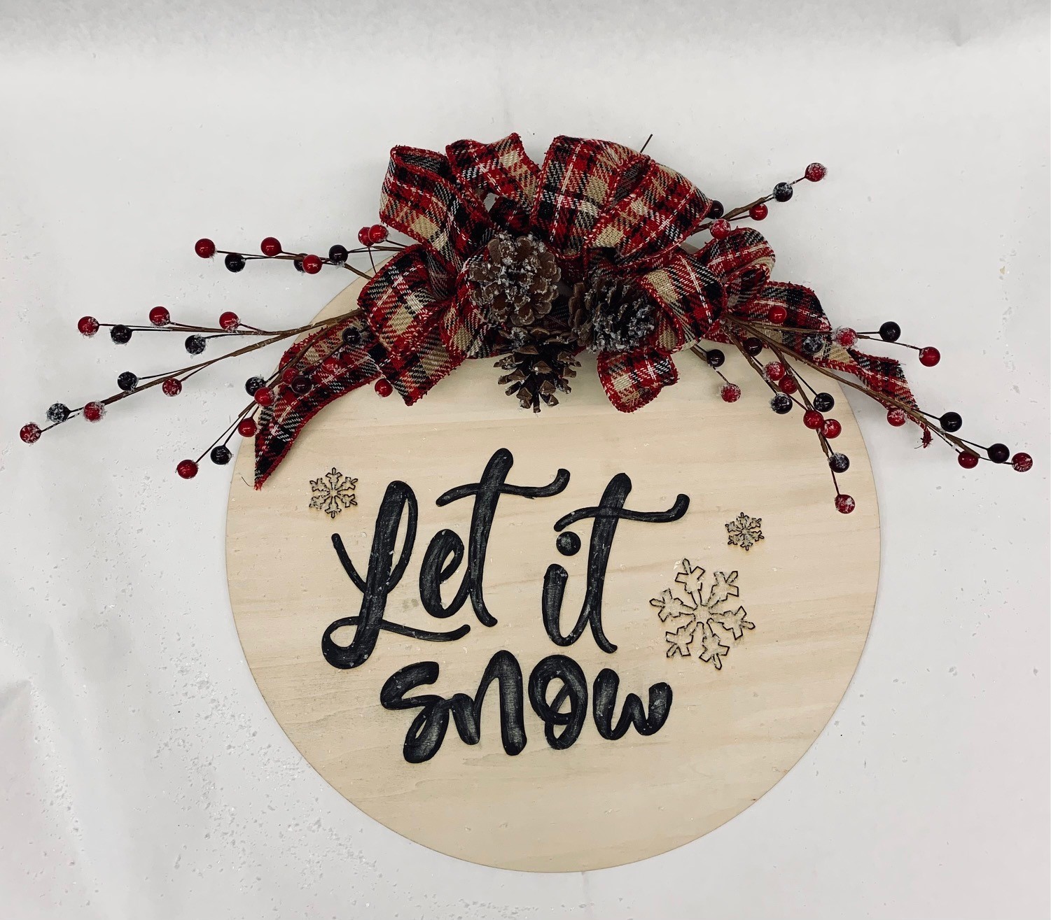 "Let it snow" text on wood circle with ribbon and berries