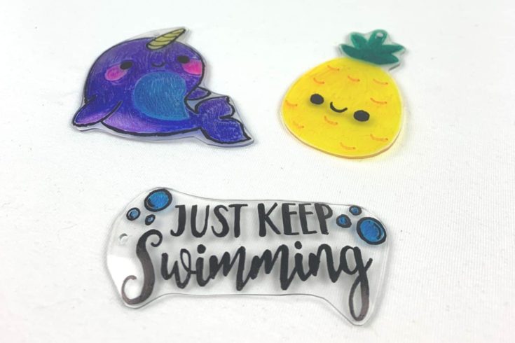 Image of shrinky dink charms of a narwhol, pineapple and "Just Keep Swimming".