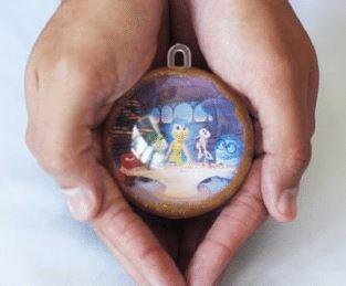 Image of hands holding an ornamentw with a picture inside.