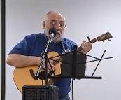 Image of an older man playing a guitar and singing.