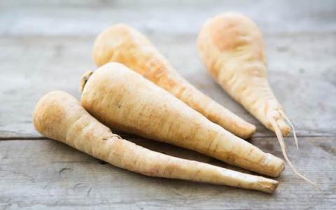 Image of raw parsnips laying on a wooden surface.