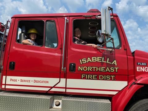 Image of a child and parent in a firetruck.