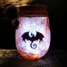 Image of a dark dragon silhouette showing through a mason jar lit from the inside.