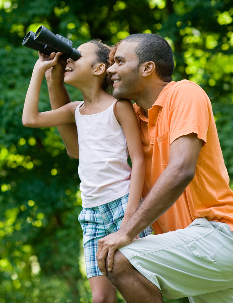 Father and daughter birdwatching, girl is using binoculars.