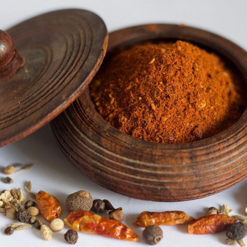 Round box with lid tipped off to the side filled with Berbere spice.