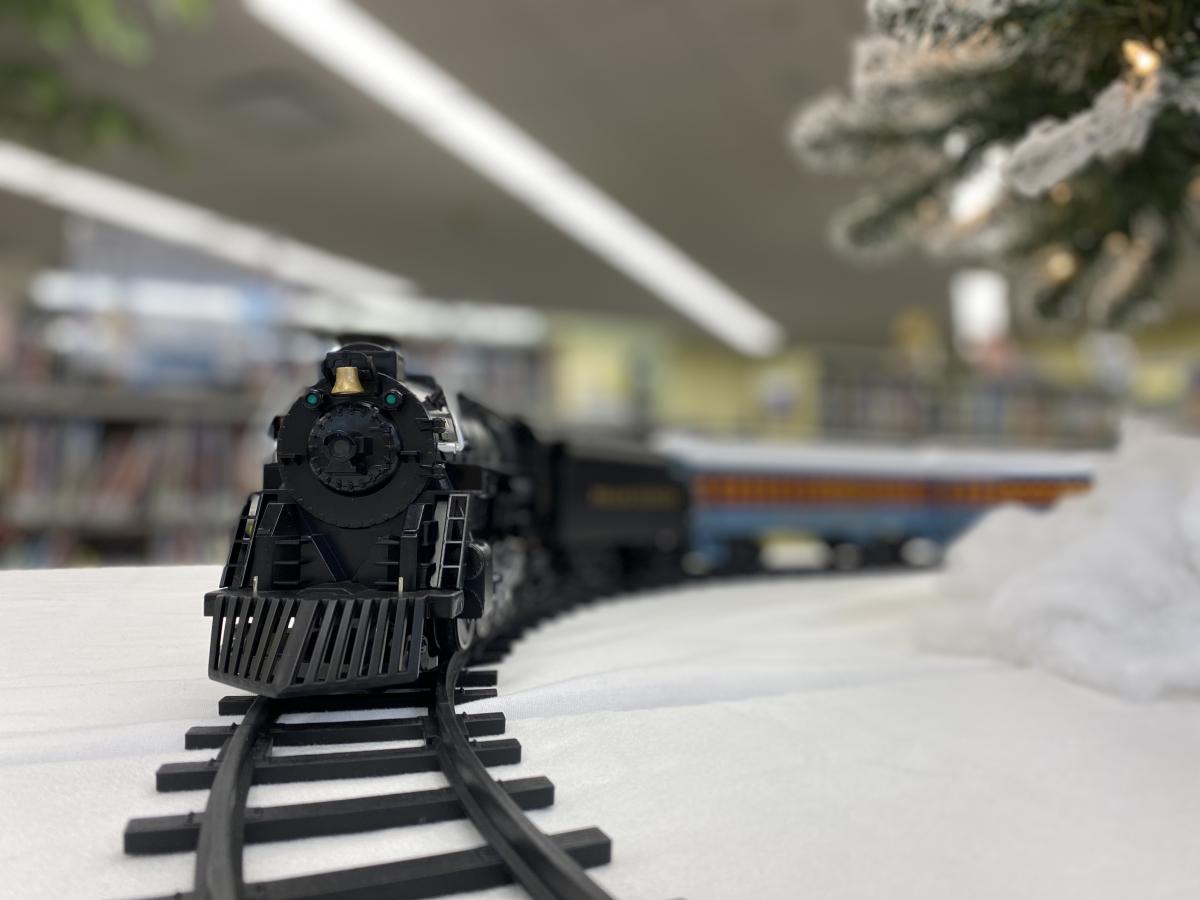 A model train on the tracks amongst a snow scene approaching the viewer.