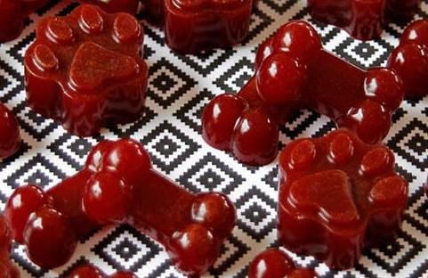 Image of dow paw-shaped red gummy treats on a table with a black and white print tablecloth.