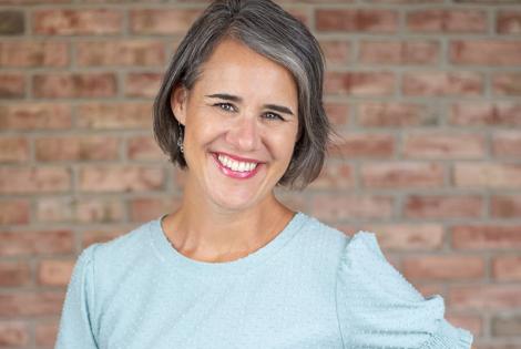 Author Katie Reid standing in front of a brick wall with her hand on her hip.